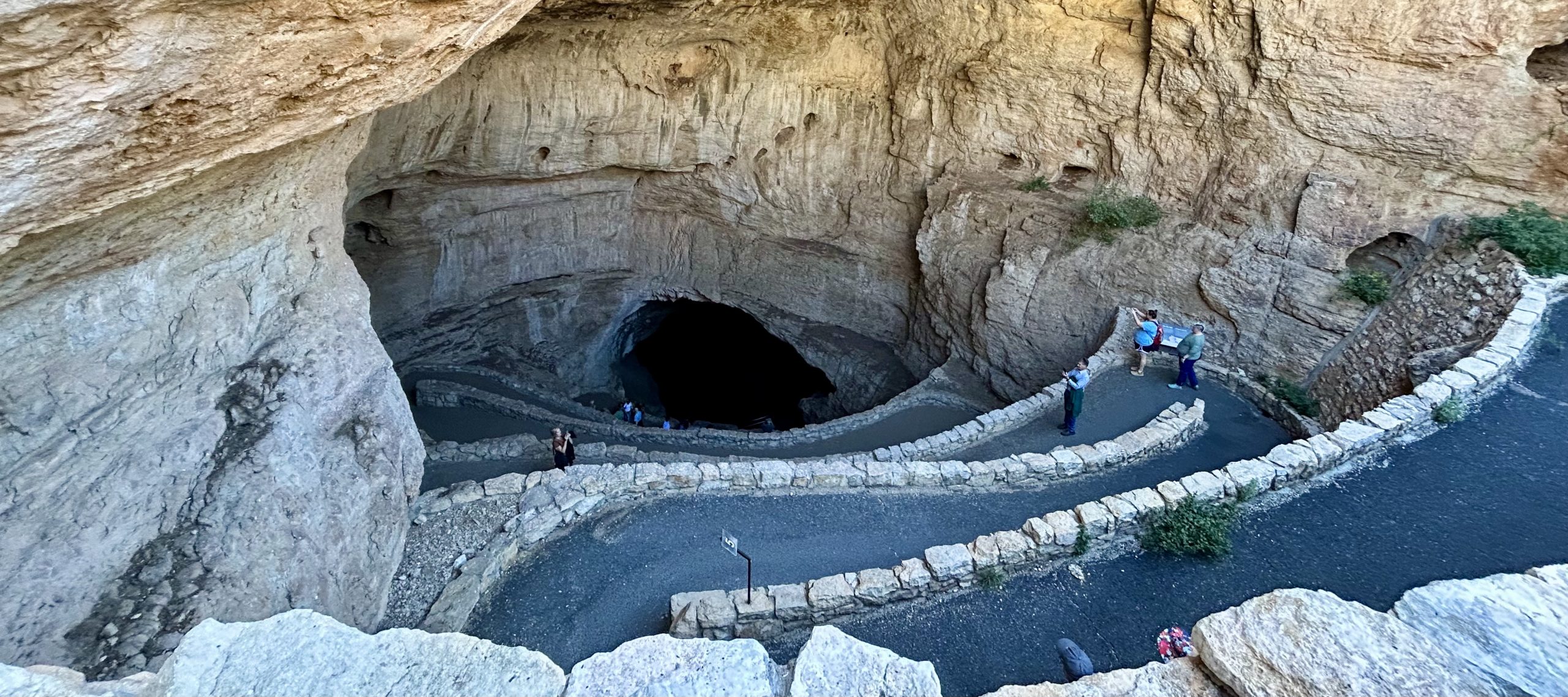 Natural entrance into the Carlsbad Caverns showing walking path switchbacks, cave wall and opening.